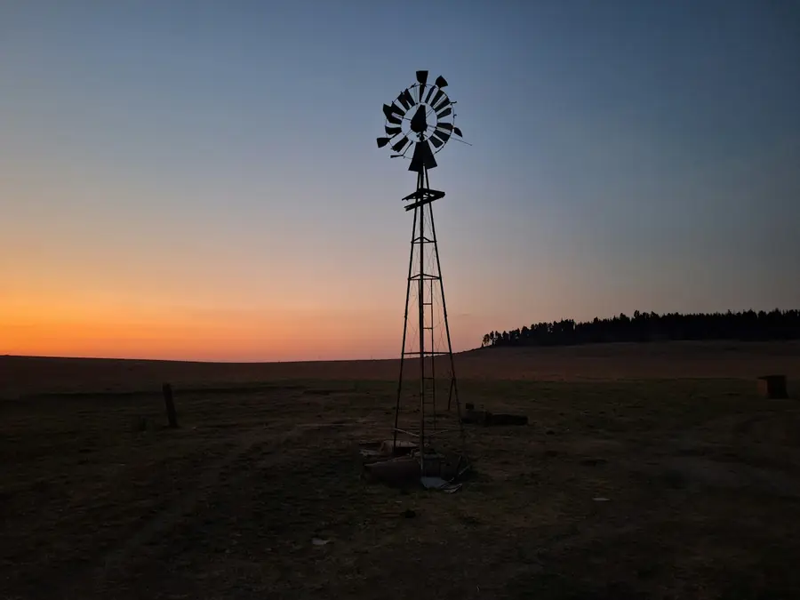 A windpump in silhouette against an orange dusk sky